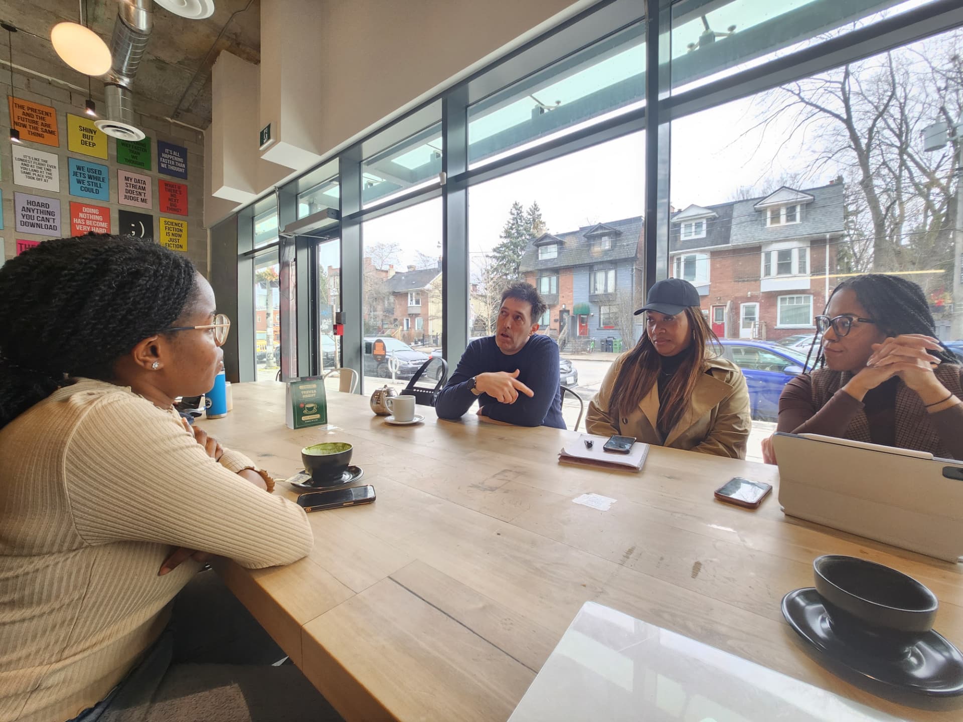 A small group in conversation around a large table in a Toronto café